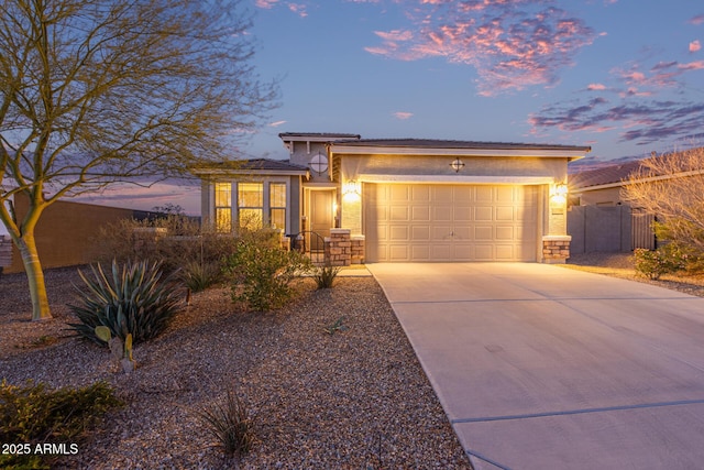 view of front facade featuring stucco siding, concrete driveway, an attached garage, and fence