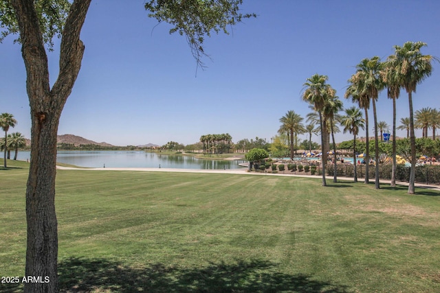 view of home's community with a water view and a lawn