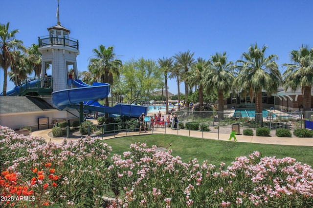 view of property's community with a swimming pool, a lawn, and fence