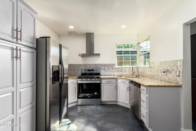 kitchen with sink, backsplash, stainless steel appliances, light stone countertops, and wall chimney exhaust hood