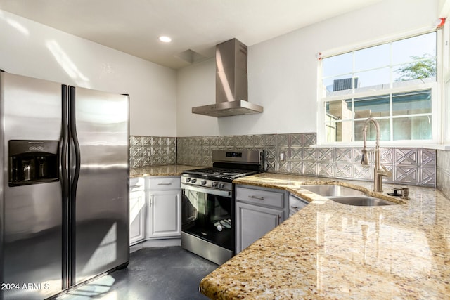 kitchen with wall chimney range hood, sink, white cabinetry, stainless steel appliances, and light stone countertops