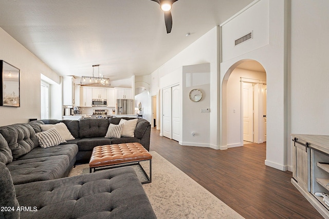 living room with ceiling fan with notable chandelier, dark hardwood / wood-style floors, and high vaulted ceiling