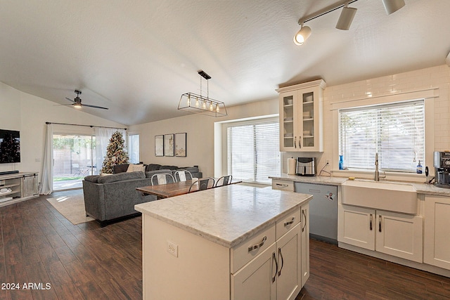 kitchen with sink, stainless steel dishwasher, dark hardwood / wood-style floors, decorative light fixtures, and vaulted ceiling