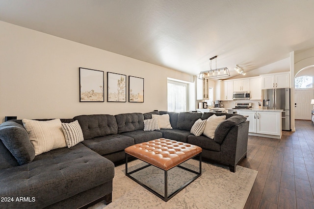 living room with hardwood / wood-style floors, a notable chandelier, and vaulted ceiling