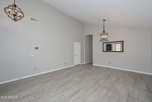 7949 W Wescott Dr, Glendale, AZ 85308 - unfurnished dining area with a chandelier, arched walkways, light wood finished floors, baseboards, and high vaulted ceiling
