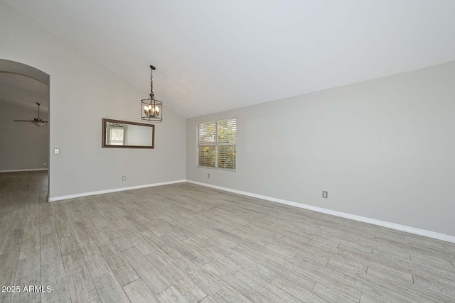 7949 W Wescott Dr, Glendale, AZ 85308 - spare room featuring arched walkways, light wood-style flooring, baseboards, vaulted ceiling, and a chandelier