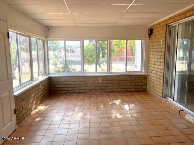 904 E Christmas Tree Ln, Pearce, AZ 85625 - unfurnished sunroom with brick wall, healthy amount of natural light, a drop ceiling, and tile patterned flooring