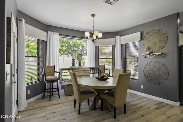 dining space with light wood-type flooring, baseboards, a chandelier, and visible vents