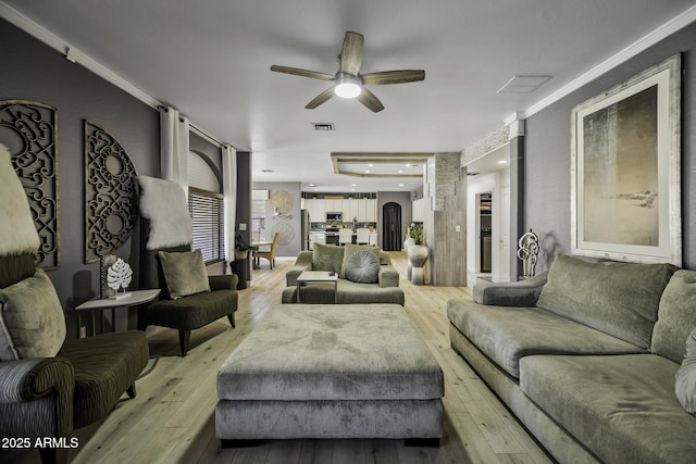 living area with a ceiling fan, visible vents, and light wood-style flooring