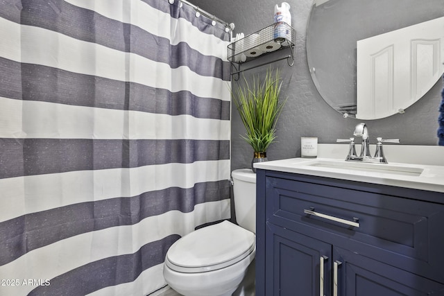 full bath with toilet, a textured wall, and vanity