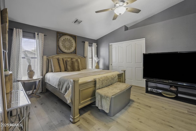 bedroom with a ceiling fan, visible vents, vaulted ceiling, a closet, and light wood finished floors