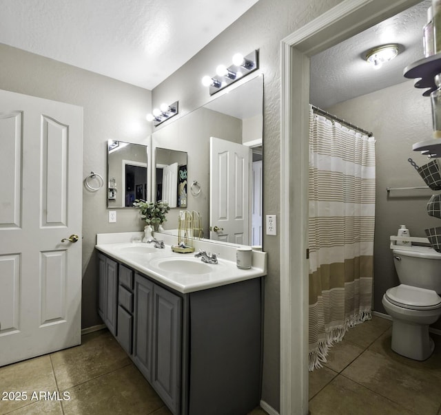 full bath with double vanity, toilet, a sink, and tile patterned flooring