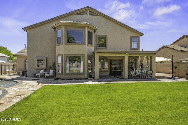 rear view of house featuring a yard, a patio, fence, and stucco siding