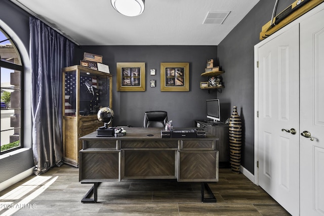 office space featuring baseboards, visible vents, and wood finished floors