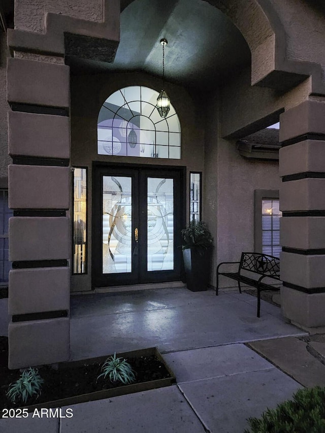 foyer entrance with french doors, vaulted ceiling, and stone tile flooring