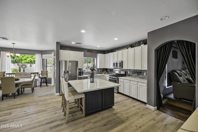 kitchen featuring white cabinets, stainless steel appliances, a healthy amount of sunlight, and tasteful backsplash