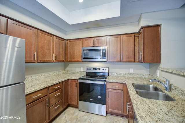 kitchen featuring light tile patterned floors, stainless steel appliances, a sink, light stone countertops, and brown cabinetry