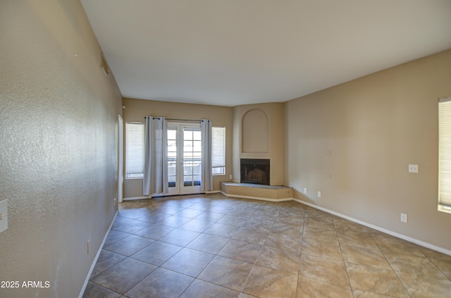 unfurnished living room featuring tile patterned flooring, a large fireplace, and baseboards