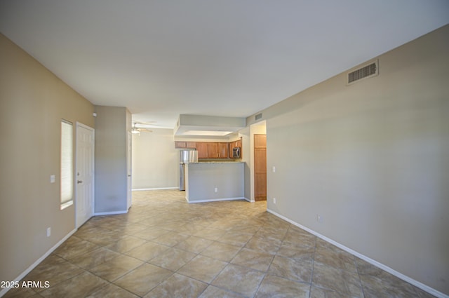 unfurnished living room featuring baseboards, visible vents, and ceiling fan