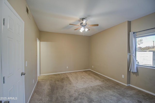 carpeted spare room featuring baseboards and a ceiling fan