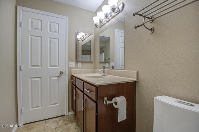 bathroom featuring a textured wall, vanity, and an inviting chandelier