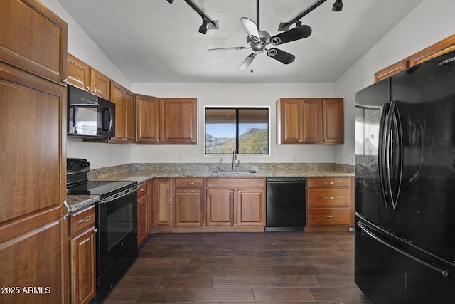 kitchen with track lighting, light stone counters, ceiling fan, sink, and black appliances