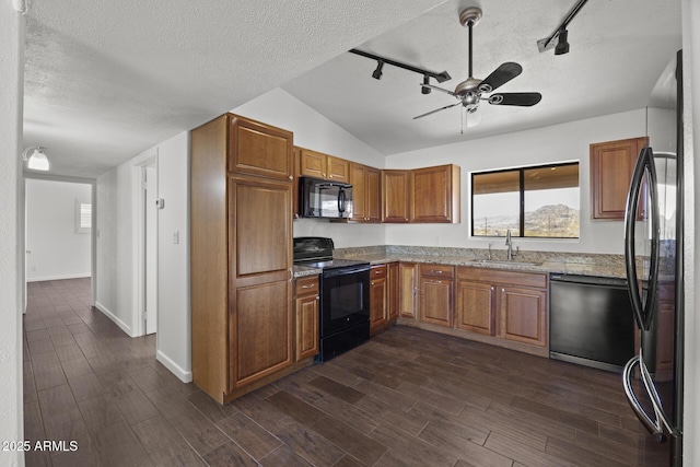 kitchen with black appliances, sink, rail lighting, ceiling fan, and light stone counters