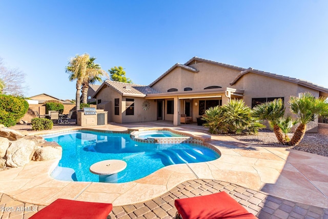 view of swimming pool featuring an in ground hot tub, an outdoor kitchen, grilling area, and a patio area