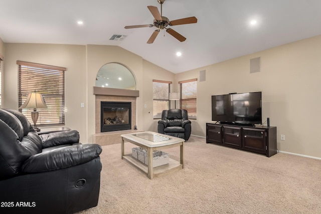 living room featuring a tiled fireplace, lofted ceiling, light colored carpet, and ceiling fan