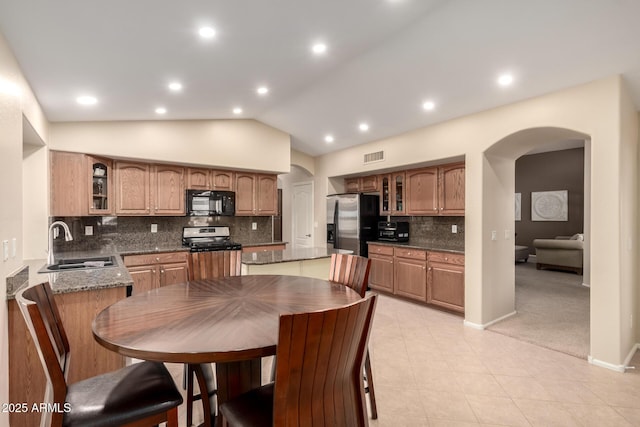 kitchen featuring appliances with stainless steel finishes, lofted ceiling, sink, dark stone counters, and a center island