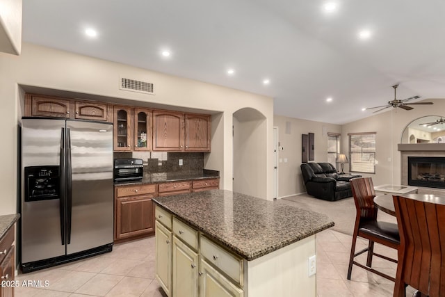 kitchen featuring a center island, dark stone countertops, stainless steel fridge, and light tile patterned floors