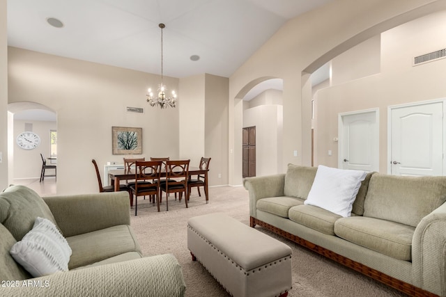 living room with a chandelier, light carpet, and high vaulted ceiling