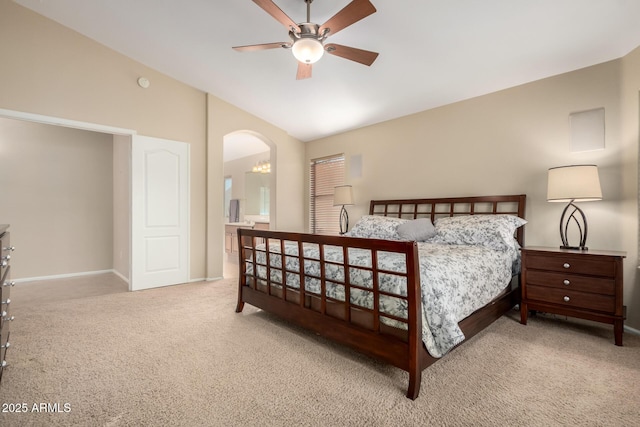 carpeted bedroom with ceiling fan, lofted ceiling, and ensuite bathroom