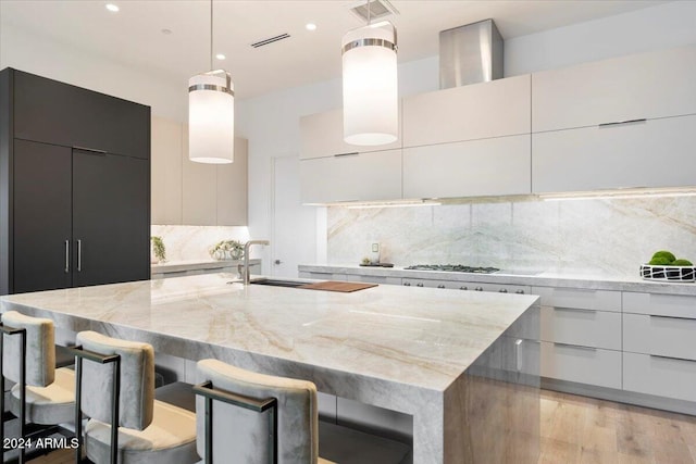 kitchen featuring a breakfast bar, light hardwood / wood-style floors, light stone counters, and hanging light fixtures