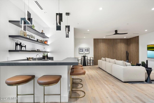 bar featuring decorative light fixtures and light hardwood / wood-style flooring