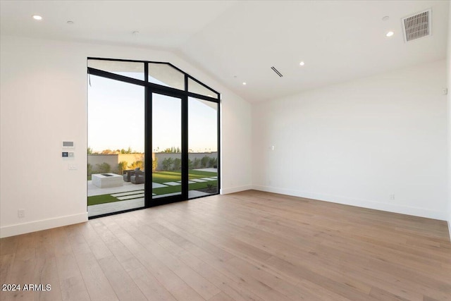 spare room with a wealth of natural light, light hardwood / wood-style flooring, and vaulted ceiling