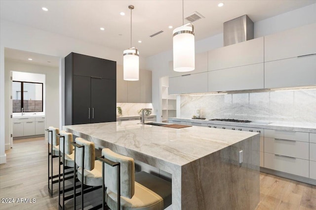 kitchen with light hardwood / wood-style floors, light stone counters, hanging light fixtures, and a large island