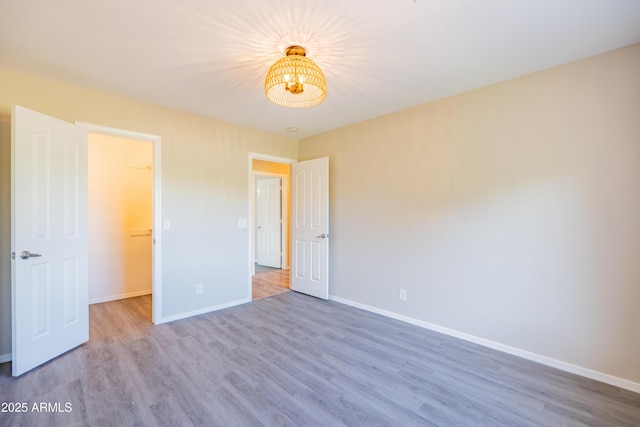 17824 E Chestnut Dr, Queen Creek, AZ 85142 - unfurnished bedroom with baseboards, wood finished floors, and a notable chandelier