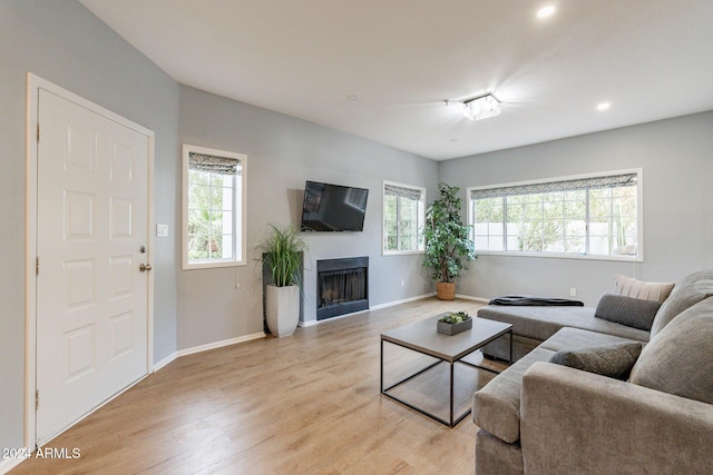 living room featuring a fireplace, light wood-style flooring, and baseboards