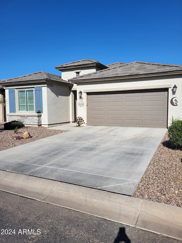 prairie-style home featuring a garage, driveway, and stucco siding