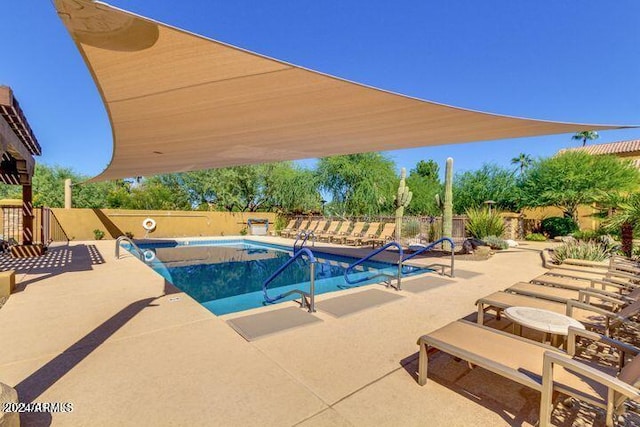 pool with a patio area and fence