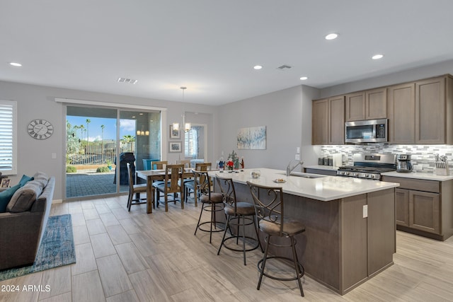 kitchen with stainless steel appliances, a breakfast bar, a sink, visible vents, and tasteful backsplash