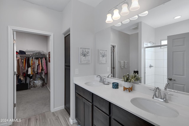 full bathroom featuring double vanity, a sink, a shower stall, and a spacious closet