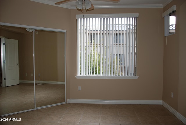 unfurnished bedroom with baseboards, tile patterned flooring, ornamental molding, and a closet