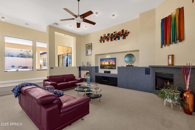 carpeted living room featuring ceiling fan and a fireplace