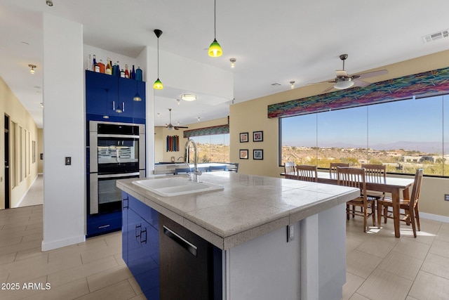 kitchen with appliances with stainless steel finishes, ceiling fan, sink, light tile patterned floors, and a center island with sink