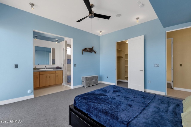 bedroom featuring a walk in closet, sink, ceiling fan, light colored carpet, and a closet