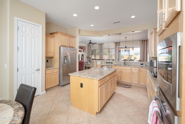 kitchen with hanging light fixtures, appliances with stainless steel finishes, kitchen peninsula, a kitchen island, and light stone countertops