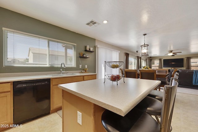 kitchen featuring a kitchen bar, decorative light fixtures, a center island, light brown cabinets, and black dishwasher