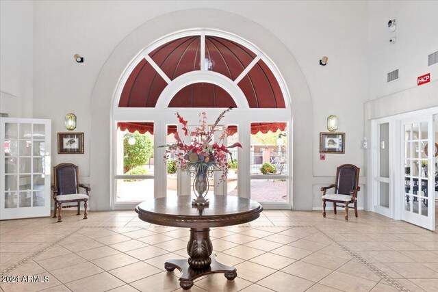 foyer entrance with a high ceiling, french doors, and light tile patterned floors